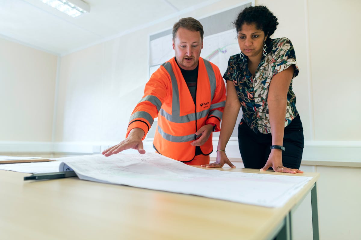 Engineer in hard hat reviewing specifications on a clipboard
